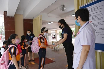 Học sinh Trường tiểu học Thăng Long (Hoàn Kiếm, Hà Nội) rửa tay sát khuẩn, kiểm tra thân nhiệt trước khi vào trường học trực tiếp. (Ảnh: Duy Linh)