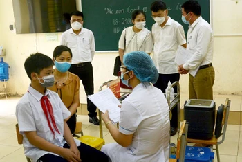 Cán bộ y tế huyện Phú Xuyên tư vấn cho phụ huynh lợi ích của tiêm vaccine và theo dõi sức khỏe sau tiêm chủng.