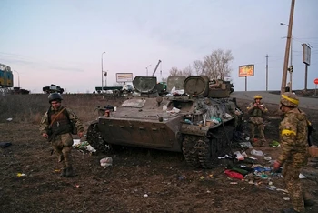 Binh sĩ Ukraine cạnh 1 chiếc xe bọc thép bị hư hại ở ngoại ô Kharkiv, Ukraine, ngày 24/2/2022. (Ảnh: Reuters)