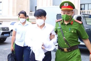 Lực lượng chức năng dẫn giải bị cáo Trương Quốc Cường tới khu vực xét xử. 