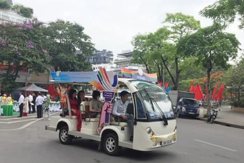 Du khách trên hành trình khám phá phố phường Hà Nội bằng xe điện.