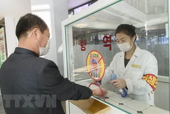 Khử khuẩn tay, đo thân nhiệt, nhằm ngăn chặn sự lây lan của dịch Covid-19 trước khi vào trung tâm thương mại ở Bình Nhưỡng, Triều Tiên. (Ảnh: AFP/TTXVN)