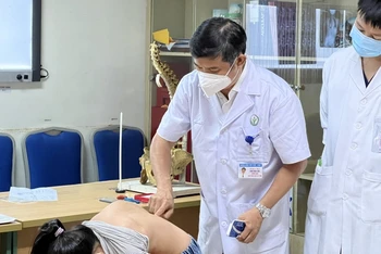PSS, TS Đinh Ngọc Sơn cùng đồng nghiệp khám cho trẻ em bị vẹo cột sống. (Ảnh: Thảo My)