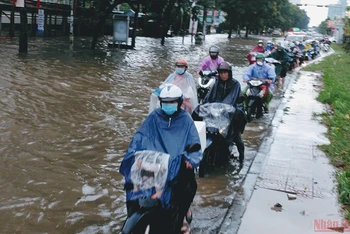 Người tham gia giao thông di chuyển khó khăn trên đường Hoàng Quốc Việt (Hà Nội) sau trận mưa lớn chiều 28/5. (Ảnh: Đăng Khoa)