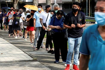 Người dân xếp hàng chờ xét nghiệm nhanh SARS-CoV-2 tại Singapore. (Ảnh: Reuters)