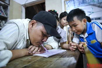 Người thầy viết chữ bằng miệng Phùng Văn Trường dạy cho các em học sinh trong làng. (Ảnh: THÀNH ĐẠT)