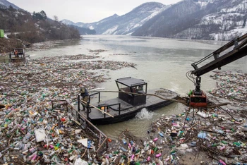  Một công nhân thu gom rác nhựa tràn ra hồ Potpecko bị ô nhiễm gần nhà máy thủy điện gần thị trấn Priboj, Serbia, ngày 29/1/2021 (Ảnh: REUTERS)