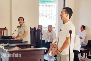 Ông L. M. T (đứng bên phải), con của bà T. T. S và ông L. T. H - người có quyền lợi và nghĩa vụ liên quan đến vụ án và bà Nguyễn Thu Hà (đứng bên trái) tại phiên tòa, sáng 25/10.