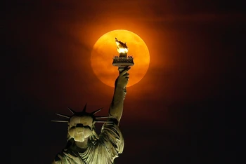 Siêu trăng mọc qua màn sương mù phía sau Tượng Nữ thần Tự do ở thành phố New York, Mỹ. (Ảnh: Getty Images)