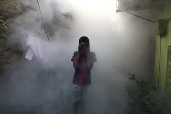 Một cậu bé che mặt để tránh khói khi khi nhân viên y tế hun khói đuổi muỗi phòng sốt xuất huyết tại một khu dân cư ở Colombo, Sri Lanka, ngày 12/7/2023. (Ảnh: Reuters)
