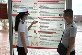 Kiểm dịch viên của Trung tâm Kiểm dịch y tế quốc tế Quảng Ninh tuyên truyền về bệnh đậu mùa khỉ tại Cửa khẩu Bắc Luân II (TP Móng Cái) cho các chủ xe. (Ảnh NGUYỄN HOA) 
