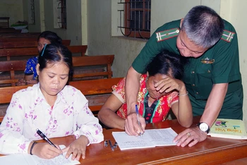Ðại úy Nguyễn Kim Trọng hướng dẫn học viên luyện viết chữ. 