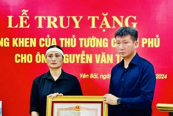 Chủ tịch Ủy ban nhân dân tỉnh Yên Bái Trần Huy Tuấn trao Bằng khen của Thủ tướng Chính phủ cho gia đình anh Nguyễn Văn Thi. (Ảnh: THANH SƠN)