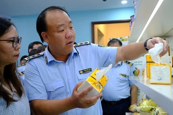 Tổng cục trưởng Quản lý thị trường Trần Hữu Linh giúp khách tham quan phân biệt sản phẩm giấy ăn thật - giả.