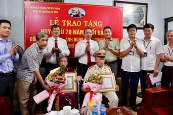 Đồng chí Nguyễn Quốc Chung, Phó Bí thư Thường trực Tỉnh ủy (thứ tư hàng sau từ trái qua) trao Huy hiệu 70 năm tuổi Đảng tặng vợ chồng Anh hùng lực lượng vũ trang nhân dân Tạ Lưu.