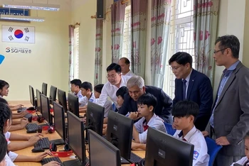 Các đại biểu hướng dẫn các em học sinh sử dụng máy tính mới.