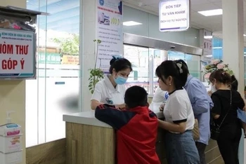 Nhân viên y tế tiếp đón và hướng dẫn người bệnh đăng ký khám bệnh tại Bệnh viện đa khoa Hà Đông. (ẢNH: DIỆU LINH)