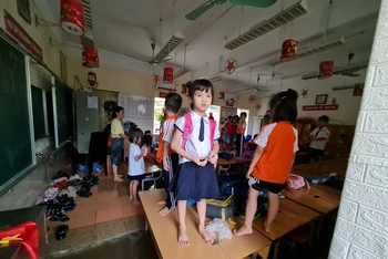 Nước tràn vào lớp tại trường Tiểu học Phú Lương 2 (quận Hà Đông) khiến cho học sinh phải đứng cả lên bàn để tránh. (Ảnh: CTV)
