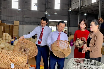 Bà Đặng Thị Dung (ngoài cùng bên phải) giới thiệu sản phẩm mây tre đan của doanh nghiệp với cán bộ Agribank.