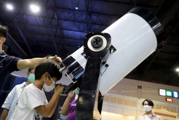 Một học sinh ngắm bầu trời qua kính thiên văn tại Hội chợ Khoa học và Công nghệ Quốc gia Thái lan 2022. (Ảnh: Bưu điện Bangkok).