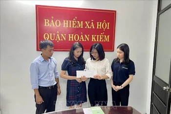 Đại diện lãnh đạo Bảo hiểm xã hội quận Hoàn Kiếm trao các chế độ tử tuất và mai táng phí cho gia đình người bị nạn. Ảnh: TTXVN phát