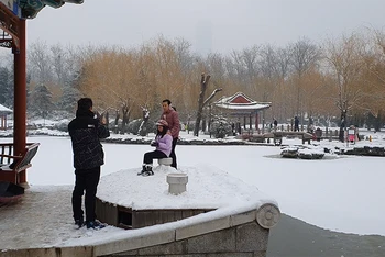 Một gia đình chụp ảnh bên mặt hồ đóng băng trong công viên Nhật Đàn. (Ảnh: HỒ QUÂN)