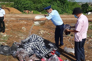 Lực lượng Quản lý thị trường tỉnh Quảng Trị tiêu hủy hàng hóa vi phạm. (Ảnh THU HÀ)