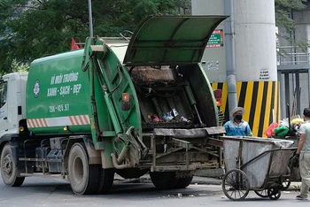 Công nhân Công ty Môi trường đô thị Hà Nội thu gom rác thải ở quận Đống Đa. (Ảnh PHẠM HÙNG)