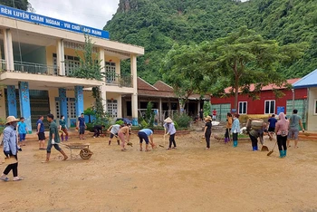 Các thầy, cô giáo và cha mẹ học sinh dọn dẹp sân trường bản Mùi II sau mưa lũ.