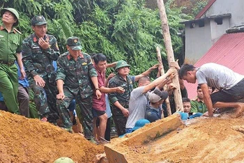 Lực lượng cứu hộ và người dân khẩn trương cứu hộ anh Lương Văn Ba bị mắc kẹt do sạt lở đất. (Ảnh: HẢI CHUNG)