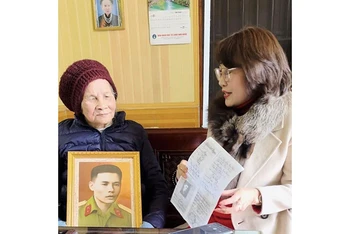 Tình nguyện viên Nguyễn Thanh Thủy trao tặng ảnh và bản chụp kỷ vật của liệt sĩ Trần Đức Ngạn cho thân nhân.