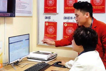 Cán bộ phường Quỳnh Lôi (quận Hai Bà Trưng) hướng dẫn người dân thực hiện dịch vụ công trực tuyến. (Ảnh: LINH NGUYỄN )
