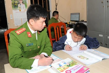 Thượng úy La Tuấn Anh, Công an xã Niêm Sơn, huyện Mèo Vạc tranh thủ dạy cháu Ly Mí Hồng học bài.