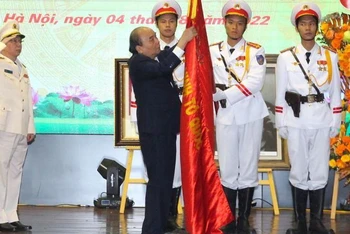Chủ tịch nước Nguyễn Xuân Phúc gắn danh hiệu Anh hùng Lực lượng vũ trang nhân dân lên Cờ truyền thống của đơn vị. (Ảnh: Báo CAND)
