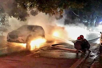 Lực lượng cứu hộ đang dập tắt đám cháy hai xe ô-tô trong đêm, ở thành phố Lào Cai.