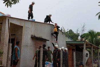 Lực lượng Cảnh sát cơ động giúp người dân thôn Nhơn Hội, xã Xuân Cảnh, thị xã Sông Cầu dùng bao cát gia cố mái che chống bão số 4.