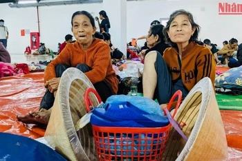 Bà Mai Thị Phi, 61 tuổi và bà Võ Thị Đố, 82 tuổi mang theo đôi dép mới và đôi nón bọc bao nylon tới điểm trú bão ở xã Bình Đông, huyện Bình Sơn.
