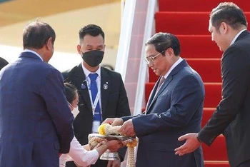 Thủ tướng Phạm Minh Chính nhận hoa chúc mừng tại sân bay quốc tế Phnom Penh. (Ảnh: VGP/Nhật Bắc)