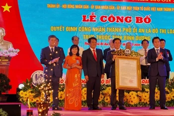 Thừa ủy nhiệm Thủ tướng Chính phủ, Thứ trưởng Xây dựng Nguyễn Tường Văn (phải) trao Quyết định công nhận thành phố Dĩ An là đô thị loại II cho lãnh đạo thành phố Dĩ An. 