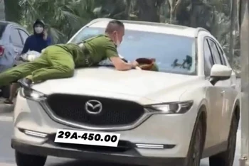 Hình ảnh vụ việc hất văng chiến sĩ Công an lên nắp ca-pô xe ô-tô. (Ảnh: TTXVN phát)