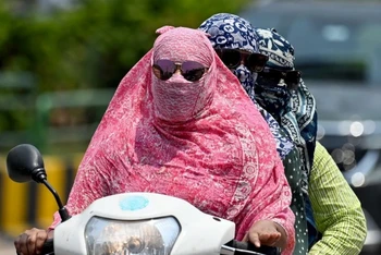 Người dân trùm kín tránh nắng nóng khi di chuyển tại Raipur, Ấn Độ. (Ảnh: AFP/TTXVN)