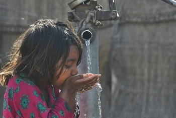 Em nhỏ uống nước từ vòi nước công cộng ở Lahore, Pakistan. (Ảnh: AFP/TTXVN)