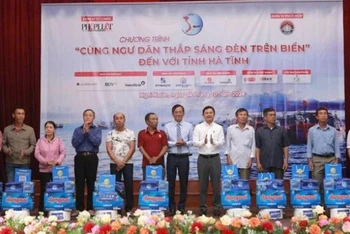 Đại diện lãnh đạo tỉnh Hà Tĩnh và báo Pháp Luật Thành phố Hồ Chí Minh trao quà cho bà con ngư dân. (Ảnh: ĐẶNG TRUNG)