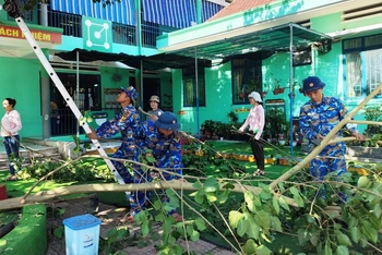 Cán bộ chiến sĩ Tiểu đoàn 863, Lữ đoàn 101 Hải quân giúp phát quang, thu dọn cây xanh trong sân trường.