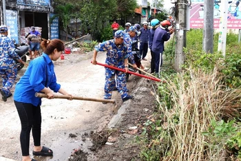 Cán bộ, đoàn viên thanh niên các đơn vị Hải quân và thanh niên địa phương dọn vệ sinh các tuyến đường giao thông ở xã Hàng Vịnh, huyện Năm Căn, tỉnh Cà Mau.