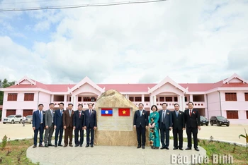 Lãnh đạo 2 tỉnh Hòa Bình và Hủa Phăn chụp ảnh lưu niệm tại biểu tượng tình hữu nghị Việt-Lào trên công trình Trường THPT huyện Hủa Mường. (Ảnh: BÙI MINH) 