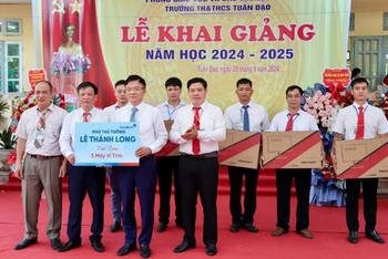 Phó Thủ tướng Lê Thành Long (phải) tặng 5 bộ máy vi tính cho Trường tiểu học và trung học cơ sở Tuân Đạo, huyện Lạc Sơn.