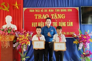 Đại diện lãnh đạo Tỉnh Đoàn Quảng Bình trao tặng huy hiệu cho 2 học sinh.