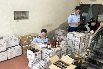 Cán bộ Cục Quản lý thị trường tỉnh Quảng Bình kiểm tra tem nhãn rượu không rõ nguồn gốc bị thu giữ. (Ảnh: Hương Giang)