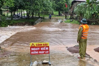 Một tuyến đường ở xã Thượng Trạch, huyện Bố Trạch bị ngập sâu, lực lượng chức năng đặt biển cảnh báo và chốt trực không cho người qua lại.